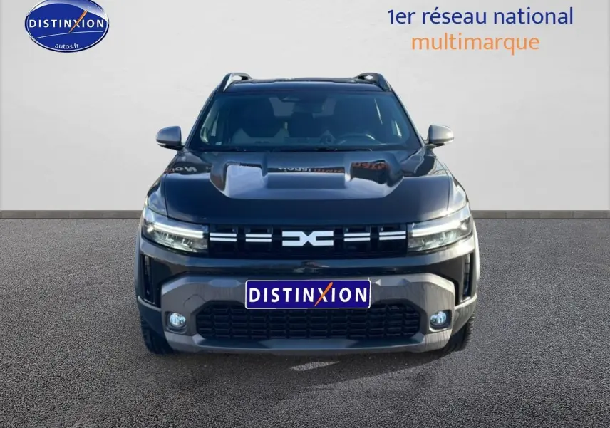 Vue avant du Dacia Duster noir 2026 avec calandre distinctive et phares LED allumés sur fond neutre.