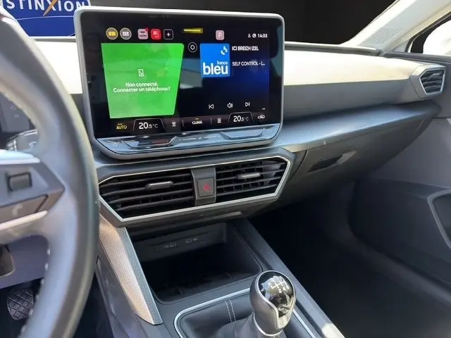 Vue intérieure côté passager du tableau de bord et console centrale d'une SEAT Leon blanche avec écran tactile et levier de vitesses manuel.