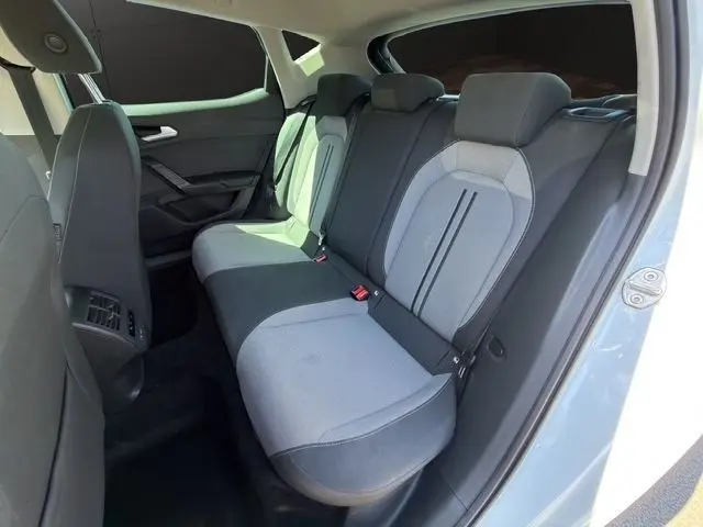 Vue intérieure côté droit des sièges arrière gris clair et foncé du SEAT Leon blanc, montrant la banquette 3 places et les appuie-têtes.