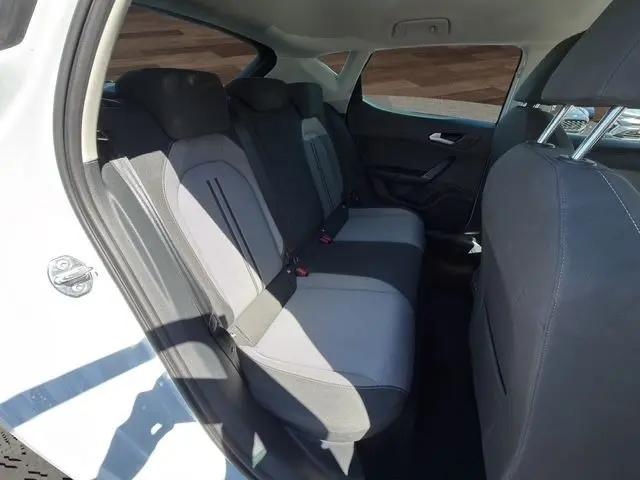 Vue intérieure arrière côté gauche du SEAT LEON blanc 2025, montrant la banquette arrière en tissu gris et noir.