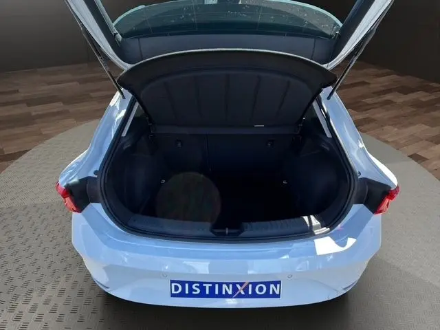 Coffre ouvert vu de l'arrière d'une SEAT LEON blanche 2025, montrant l'espace de chargement et les feux arrière LED.