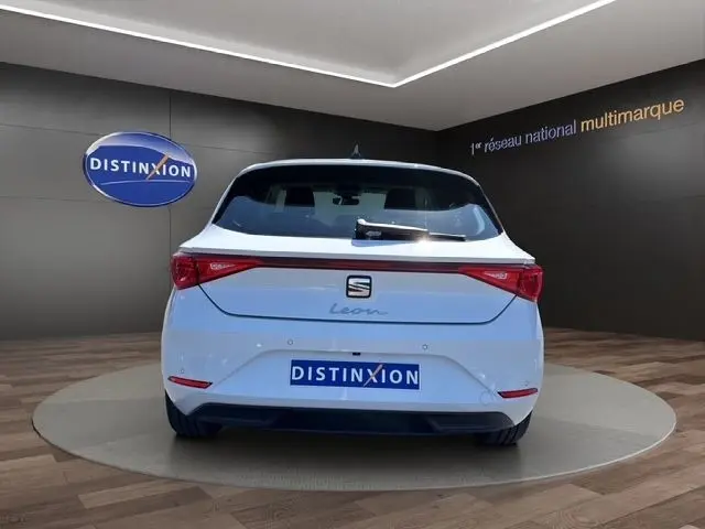 Vue arrière d'une SEAT Leon blanche 2025, avec feux LED et logo Distinxion en arrière-plan.