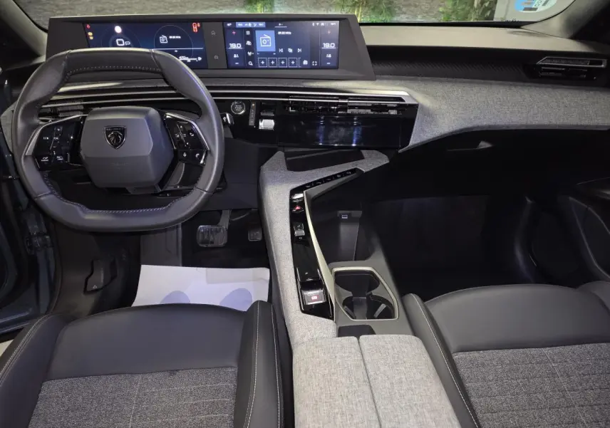 Intérieur avant du Peugeot 3008 bleu 2025, tableau de bord avec double écran HD et volant compact cuir noir.