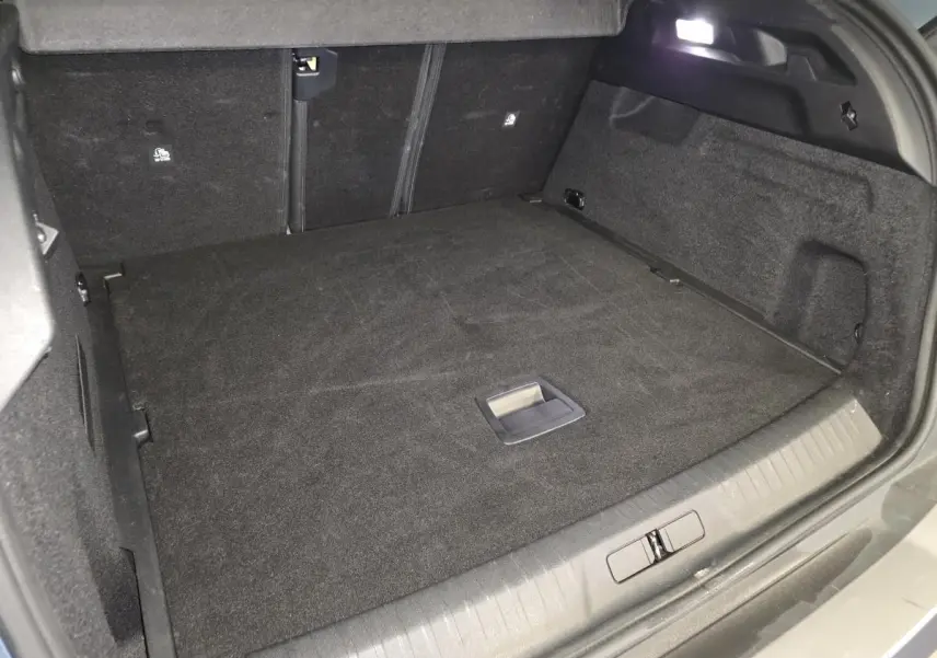 Coffre spacieux du Peugeot 3008 bleu, vue intérieure arrière avec tapis noir et éclairage LED intégré.