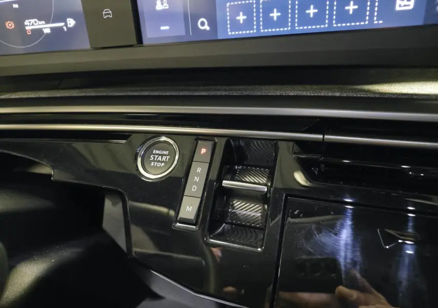 Détail de la console centrale noire laquée du Peugeot 3008 bleu, avec bouton start/stop et commandes de boîte auto.