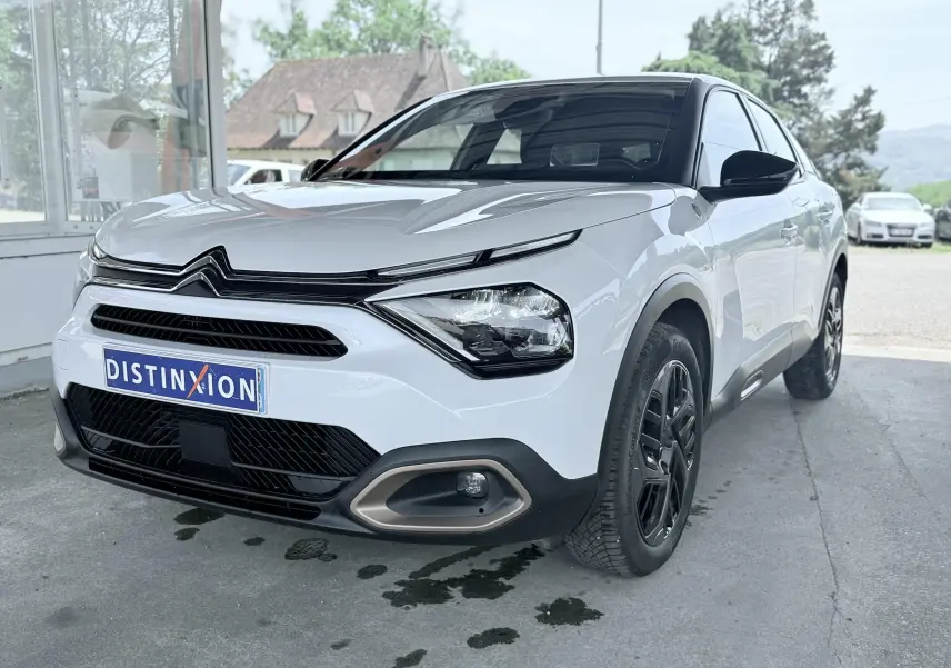 Citroën C4 blanc vue 3/4 avant droit, avec calandre noire et jantes noires contrastantes.