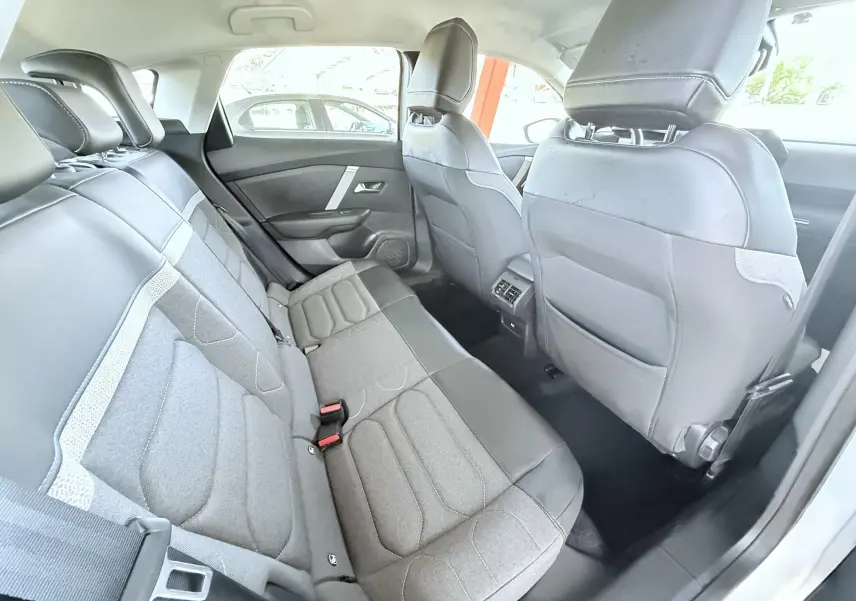 Vue intérieure arrière côté droit de la Citroën C4 2023, sièges tissu gris et cuir noir avec appuie-têtes intégrés.