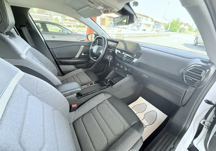 Vue intérieure côté passager de la Citroën C4 blanche 2023 avec sièges tissu gris et tableau de bord moderne.