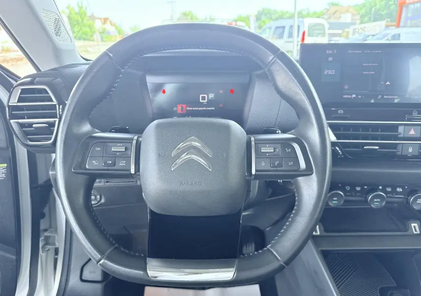 Vue centrée sur le volant noir du Citroën C4 2023 avec tableau de bord digital et écran tactile à droite.