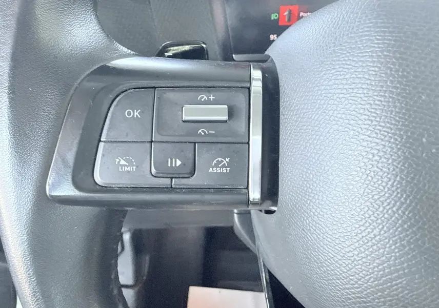 Gros plan sur les commandes de régulateur et limiteur de vitesse au volant noir d'une Citroën C4 blanche de 2023.