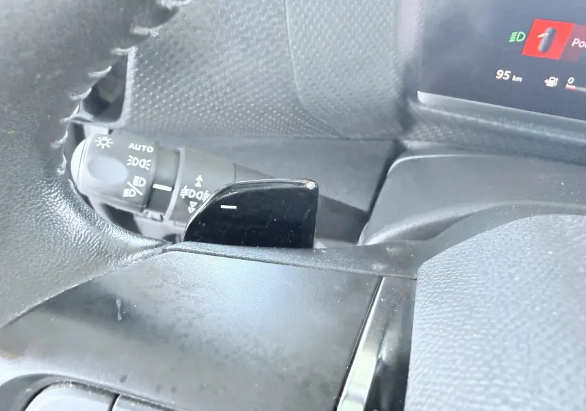 Gros plan sur la palette de changement de vitesse noire côté gauche du volant d’une Citroën C4 blanche.