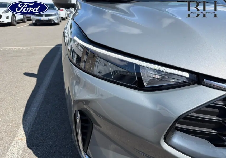 Gros plan sur l'avant droit gris Solar métallisé du Ford Kuga 2024, mettant en valeur le phare LED et la calandre.