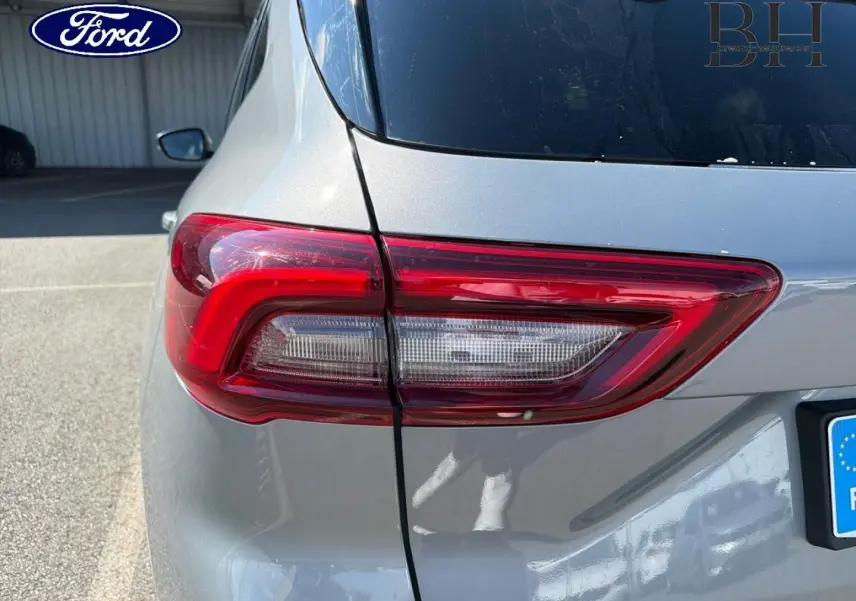 Gros plan sur le feu arrière gauche d’un Ford Kuga gris Solar métallisé, avec partie de la lunette arrière visible.