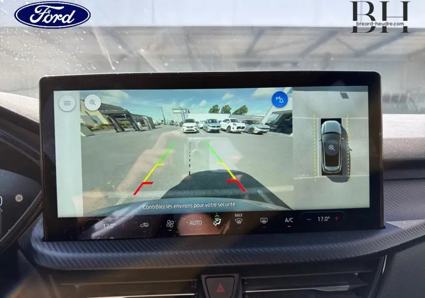 Écran tactile intérieur du Ford Kuga 2024 montrant la caméra de recul avec vue panoramique et aide au stationnement.