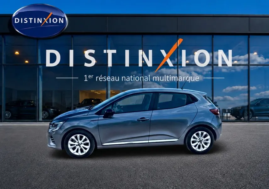 Profil droit d'une Renault Clio V gris foncé 2025 garée devant une vitrine avec logo Distinxion.