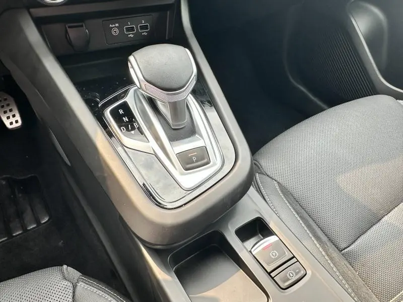 Gros plan sur la console centrale noire avec levier de boîte automatique et siège en tissu gris du Renault Arkana hybride 2023.