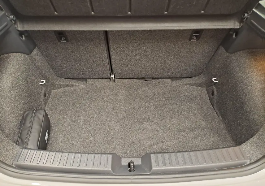 Coffre ouvert de la SEAT Ibiza blanc candy 2023, vue intérieure montrant un espace de rangement propre et un kit de secours noir.