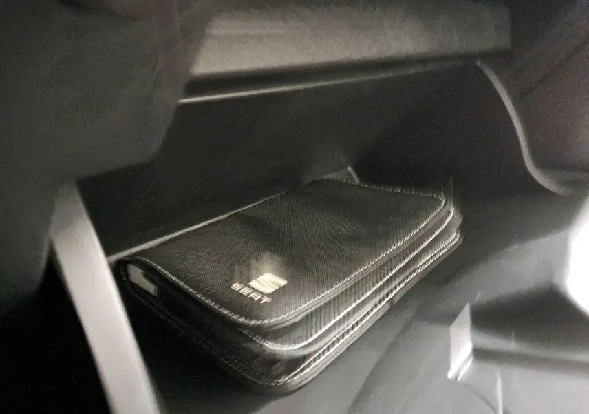 Pochette noire avec logo SEAT dans la boîte à gants d'une SEAT Ibiza blanc candy 2023, version Style Business.