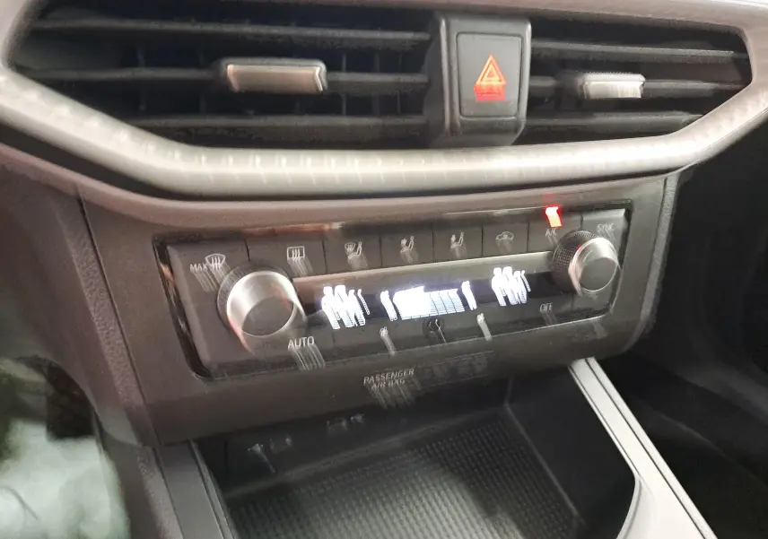 Vue rapprochée du tableau de bord de la SEAT Ibiza 2023, montrant la commande de climatisation et les aérateurs noirs.