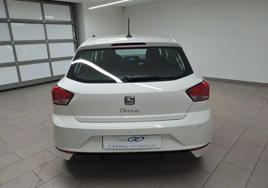 Vue arrière d'une SEAT Ibiza blanche Candy 2023, avec feux rouges anguleux et logo distinctif au centre du hayon.