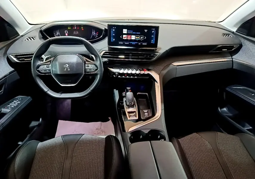 Vue intérieure avant du Peugeot 3008 gris foncé, tableau de bord moderne avec écran tactile et volant cuir multifonctions.