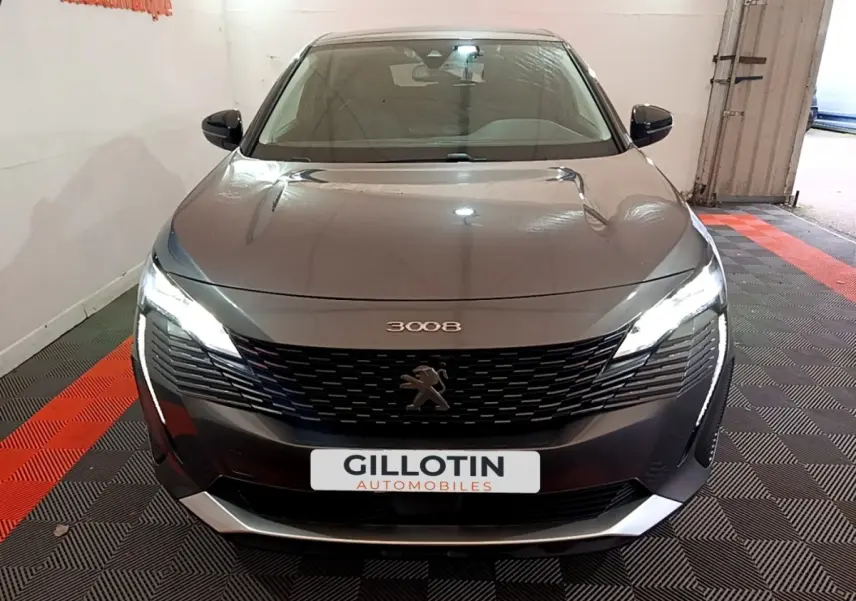 Vue avant d'un Peugeot 3008 gris foncé 2022 avec phares LED allumés et calandre noire distinctive.