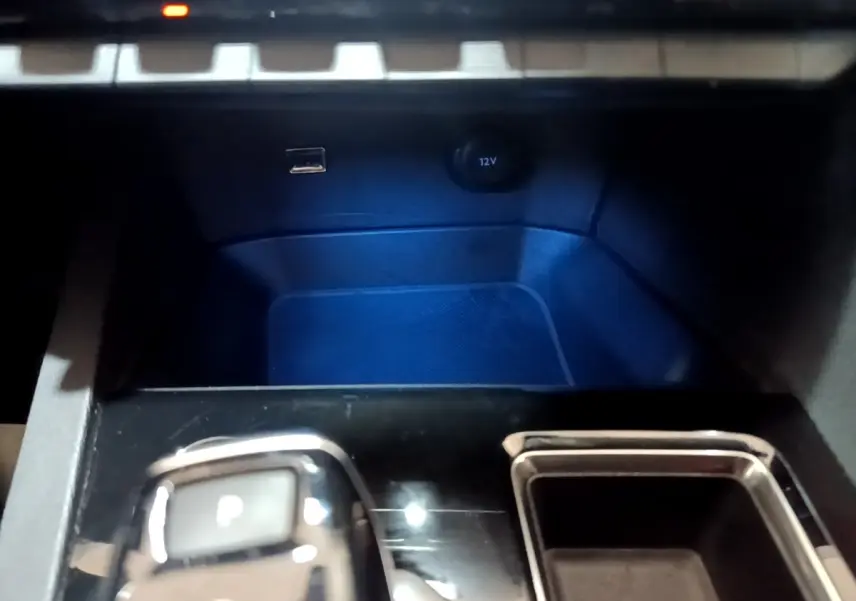 Gros plan sur la console centrale noire du Peugeot 3008 gris foncé, avec sélecteur de boîte automatique et prise 12V visible.