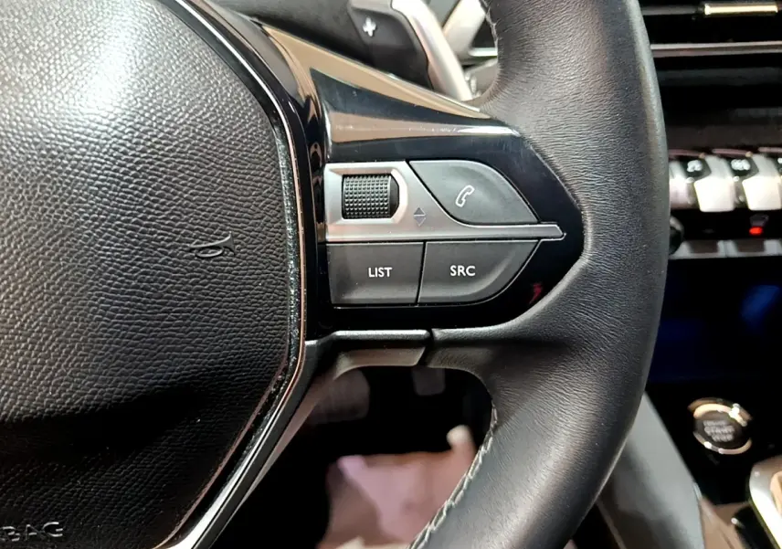 Gros plan sur les commandes gauche du volant cuir noir du Peugeot 3008 2022 BlueHDi Allure Pack.