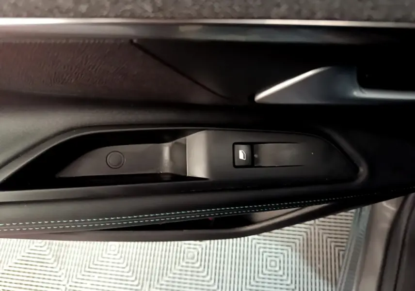 Gros plan sur la commande de lève-vitre côté gauche avec surpiqûres bleues sur la garniture intérieure noire du Peugeot 3008 gris foncé.