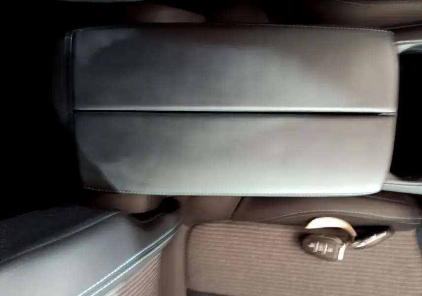 Gros plan sur l'accoudoir central en cuir noir et la clé intelligente posée sur le siège marron du Peugeot 3008 2022.