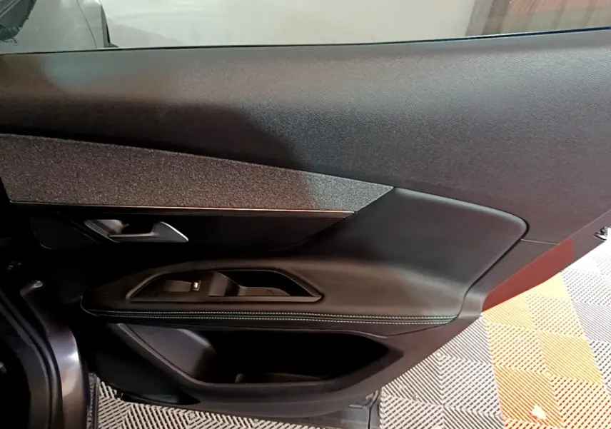Gros plan sur la porte côté gauche du Peugeot 3008 gris foncé, mettant en valeur les commandes de vitre et la poignée intérieure.