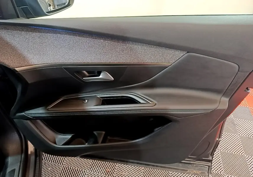 Porte intérieure côté gauche noire du Peugeot 3008 2022 avec poignée argentée et finition cuir.