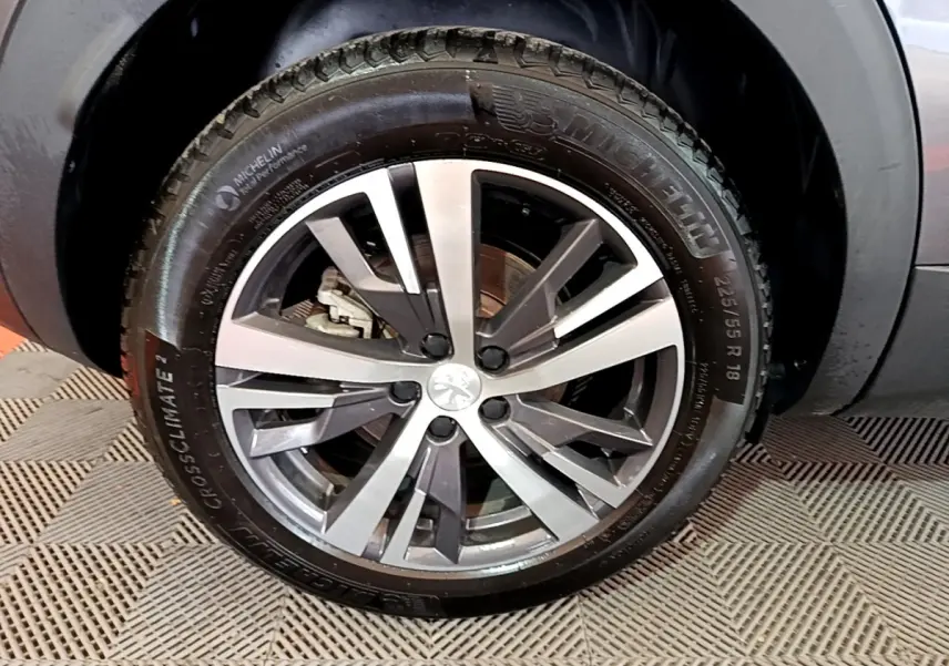 Gros plan sur la roue avant gauche avec jante alliage bicolore du Peugeot 3008 gris foncé 2022.