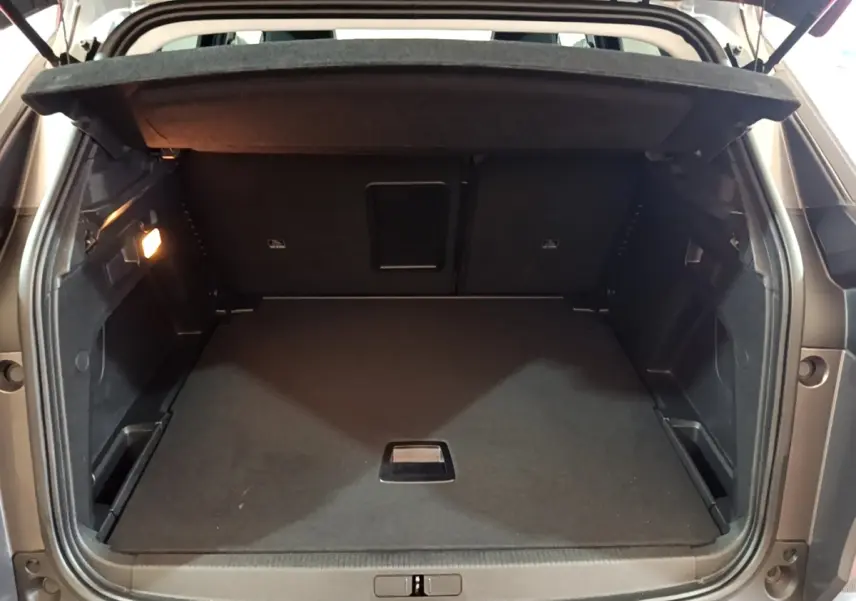 Coffre ouvert d’un Peugeot 3008 gris foncé, vue arrière montrant l’espace de chargement vide et la tablette cache-bagages.
