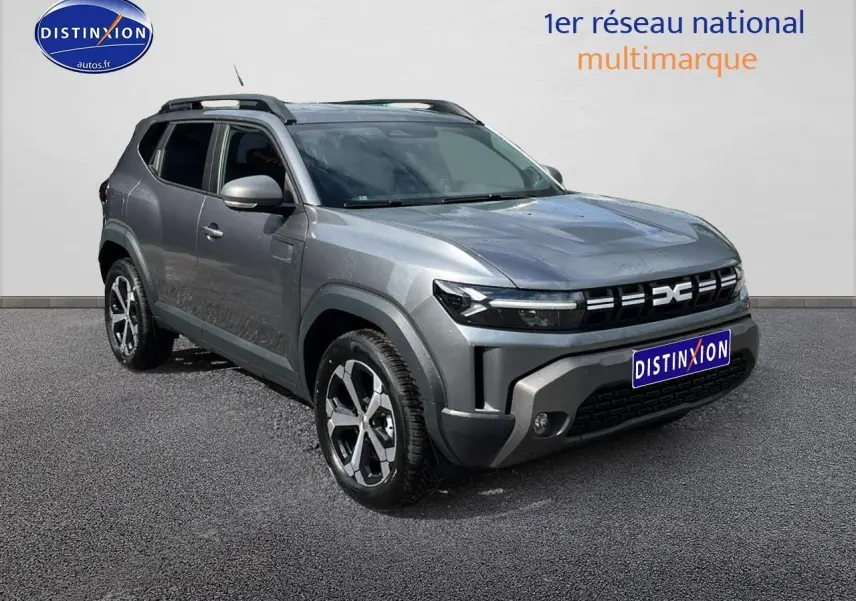 Vue 3/4 avant droit du Dacia Duster gris schiste avec barres de toit et jantes alliage distinctives.
