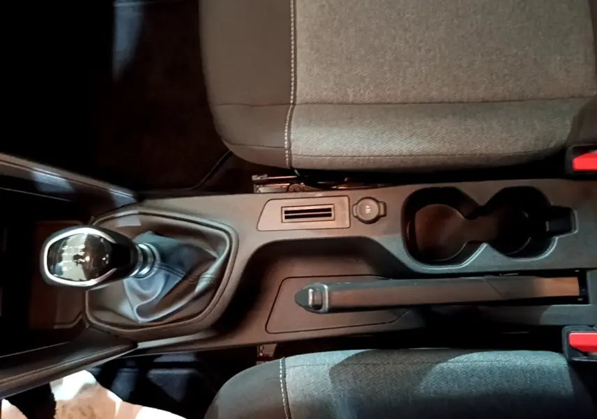 Vue plongeante sur la console centrale de la Citroën C4 gris foncé, avec frein à main manuel et porte-gobelets.