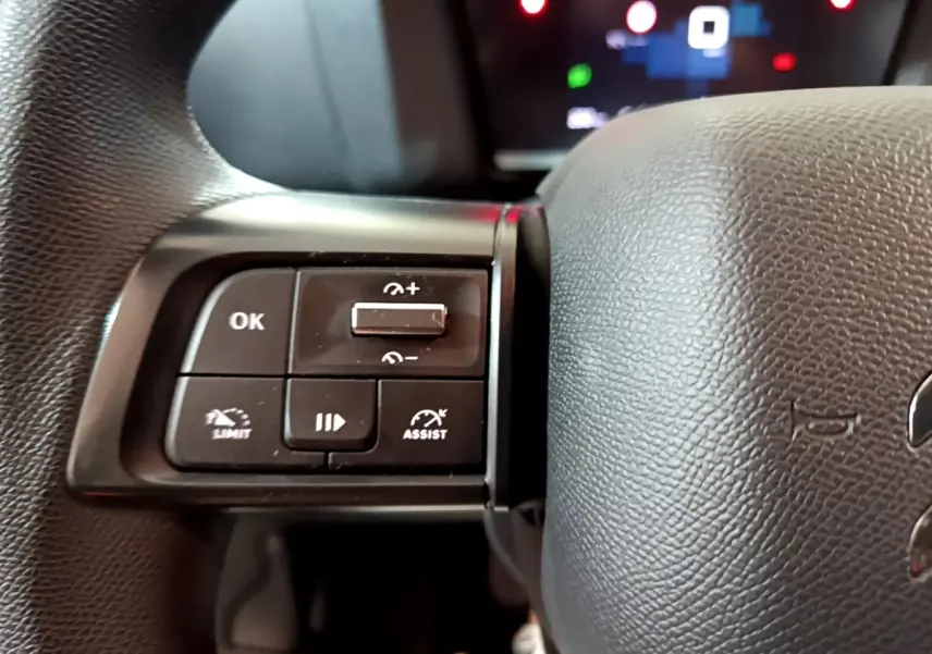 Gros plan sur les commandes multifonctions à gauche du volant noir de la Citroën C4 gris foncé, version 2021.