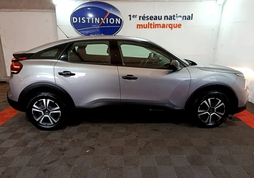 Vue de profil côté gauche d'une Citroën C4 gris foncé 2021 avec jantes alliage et feux arrière LED allumés.