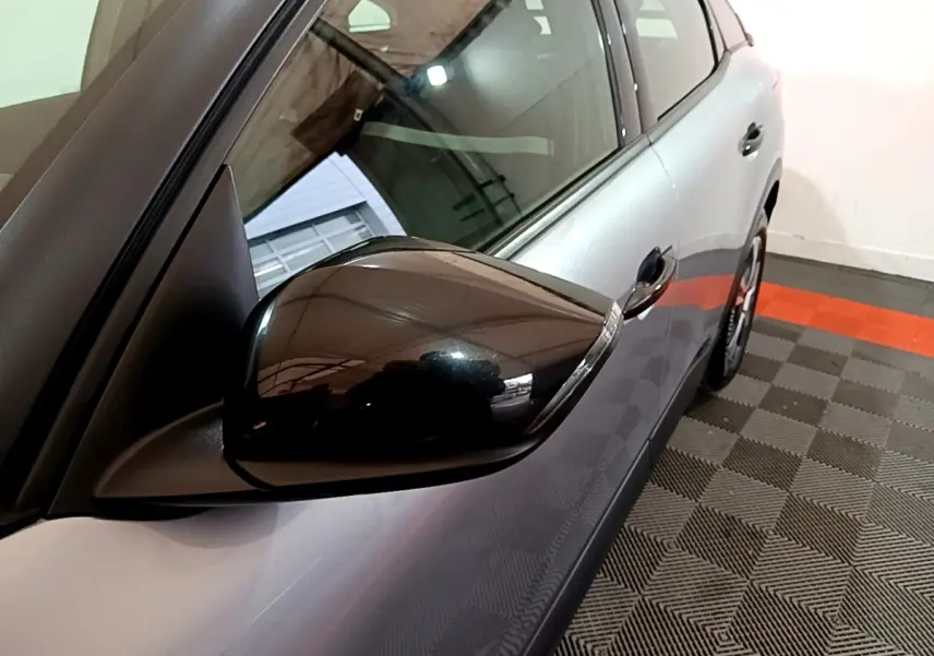 Vue rapprochée du rétroviseur droit noir sur la carrosserie gris foncé d'une Citroën C4 2021.