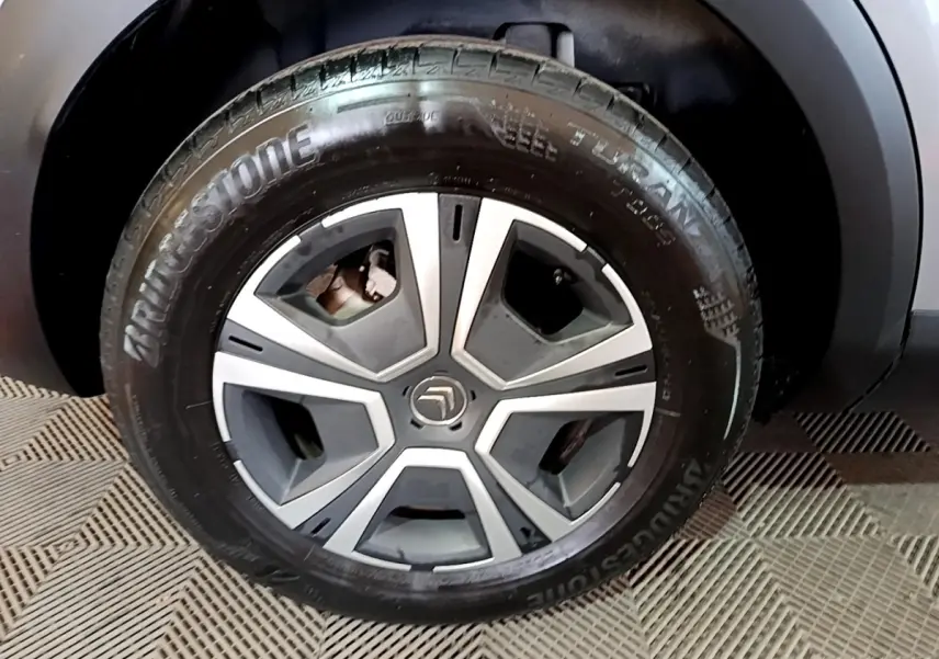 Gros plan sur la roue avant droite d'une Citroën C4 gris foncé, avec jante alliage et pneu Bridgestone.