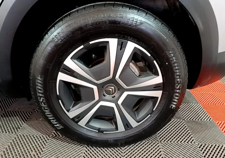 Gros plan sur la roue avant droite d'une Citroën C4 gris foncé, avec jante alliage et pneu Bridgestone.