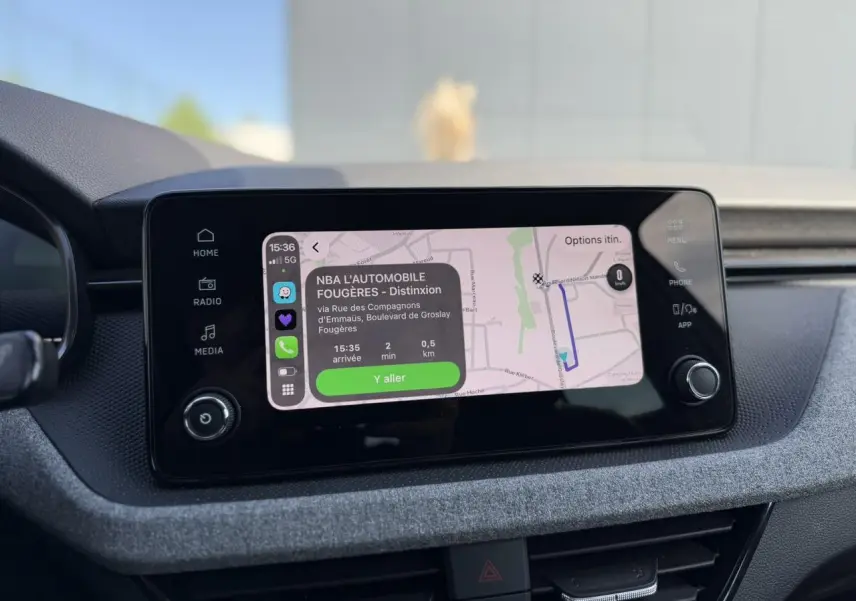 Écran tactile central de la Skoda Scala TSI 116 blanc, affichant la navigation avec itinéraire en cours.