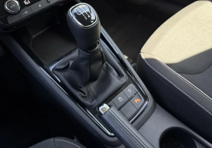 Gros plan sur la console centrale de la Skoda Scala TSI 116 blanche, avec levier de vitesse manuel et frein à main cuir.
