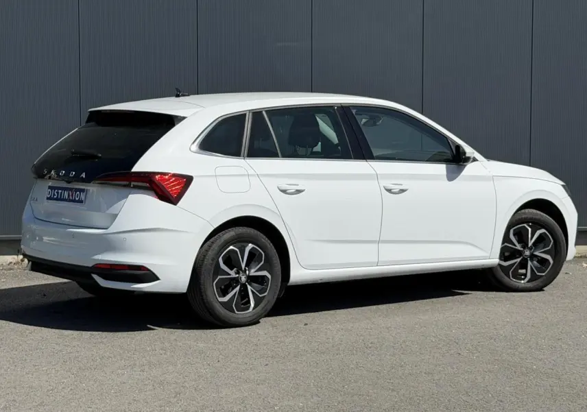 Vue 3/4 arrière droite d'une Skoda Scala blanc glacier avec vitres arrière surteintées et jantes alliage noires.
