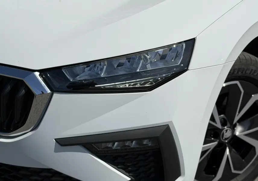 Gros plan sur l'avant droit de la Skoda Scala blanc glacier, mettant en valeur le phare LED et la jante alliage.