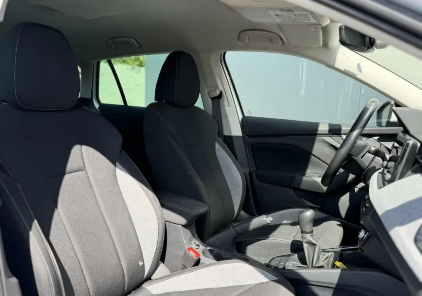 Intérieur de la Skoda Scala TSI 116 blanc Glacier vu côté droit, sièges tissu noir et gris avec accoudoir central.