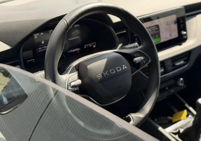 Vue rapprochée du volant cuir noir Skoda SCALA TSI 116 avec tableau de bord digital et écran tactile à droite.