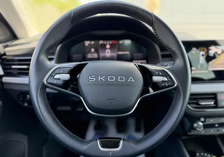 Vue frontale du volant en cuir noir marqué SKODA dans l'habitacle moderne du SCALA 2025 avec écran digital en arrière-plan.