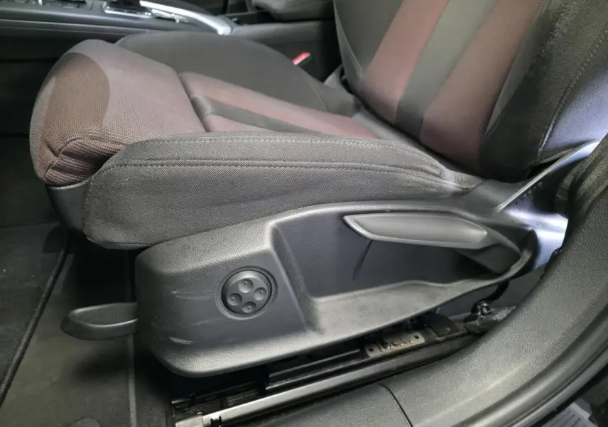 Gros plan sur le siège avant gauche de l'Audi A4 2019 avec réglages manuels et tissu bicolore noir et marron.