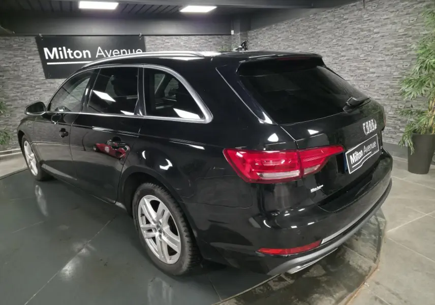Audi A4 Avant noire vue en 3/4 arrière droit, avec jantes aluminium 17 pouces et rétroviseurs noir brillant.